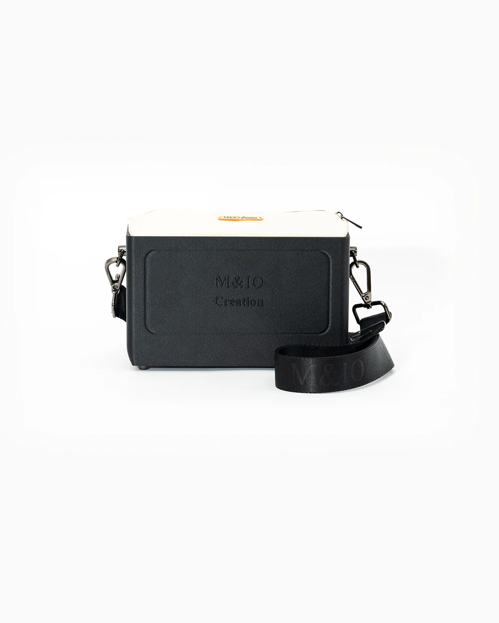 Borsa M&IO 01 di tre quarti: scocca black stone opaca con la scritta M&IO Creation in rilievo sul fronte, pochette bianco panna che sporge dal bordo superiore, cinghia in tessuto nero con logo M&IO ripetuto.