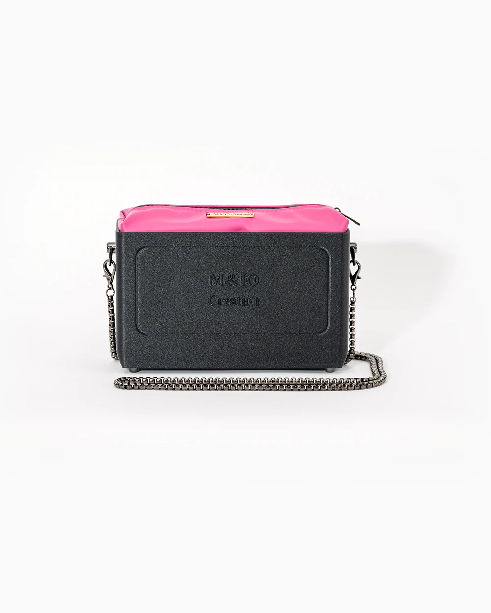 Borsa M&IO 01 di tre quarti: scocca black stone opaca con la scritta M&IO Creation in rilievo sul fronte, pochette fucsia che sporge dal bordo superiore, catena in metallo canna di fucile.