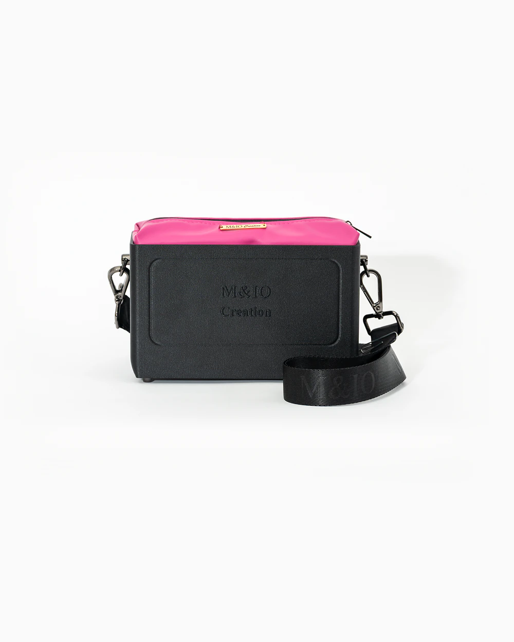 Borsa M&IO 01 di tre quarti: scocca black stone opaca con la scritta M&IO Creation in rilievo sul fronte, pochette fucsia che sporge dal bordo superiore, cinghia in tessuto nero con logo M&IO ripetuto.