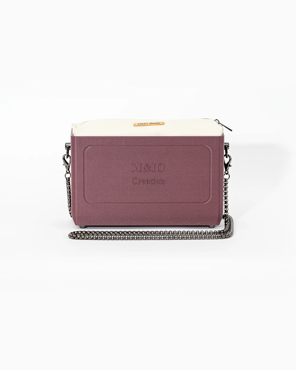 Borsa M&IO 01 di tre quarti: scocca rosso tropea opaca con la scritta M&IO Creation in rilievo sul fronte, pochette bianco panna che sporge dal bordo superiore, catena in metallo canna di fucile.