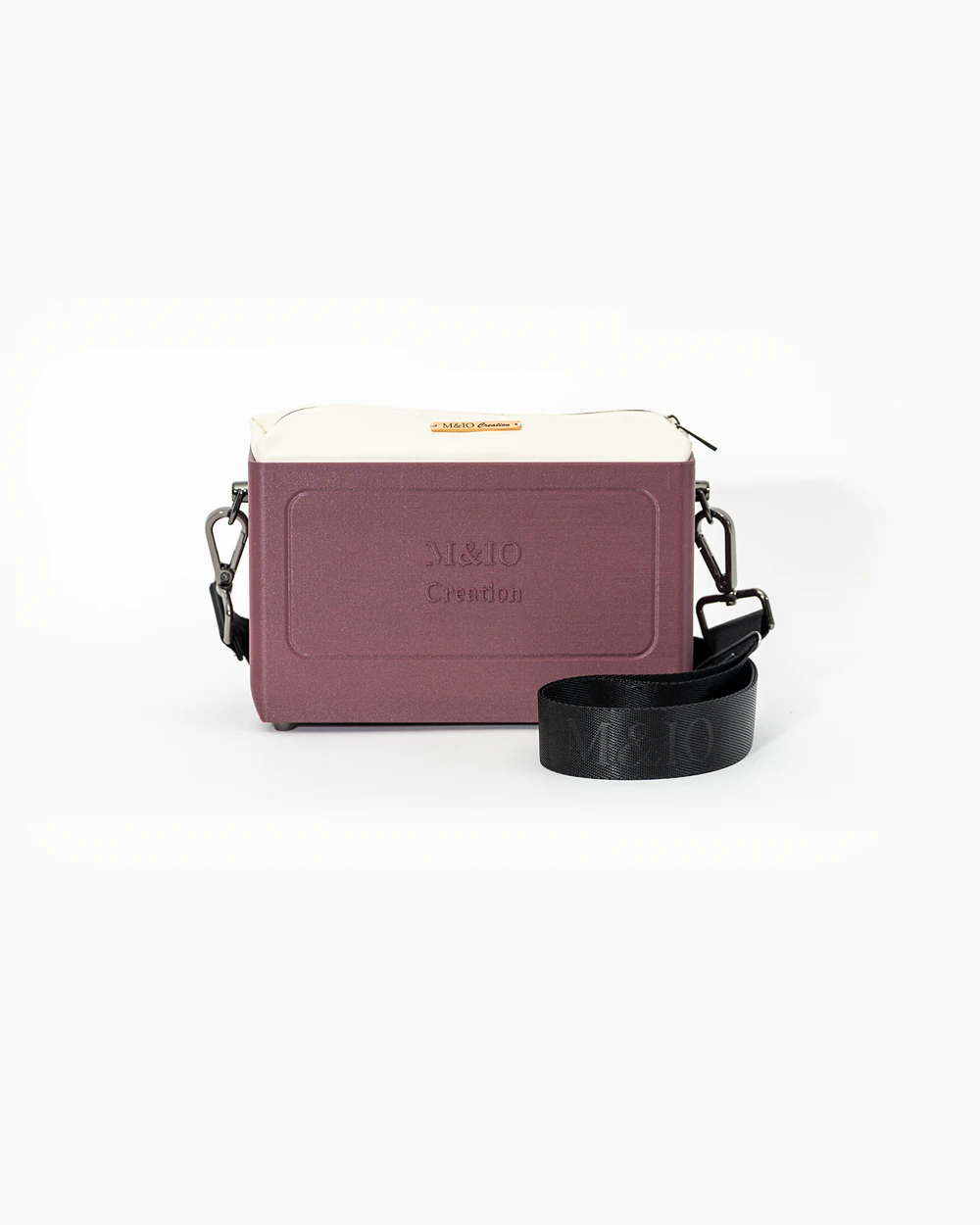 Borsa M&IO 01 di tre quarti: scocca rosso tropea opaca con la scritta M&IO Creation in rilievo sul fronte, pochette bianco panna che sporge dal bordo superiore, cinghia in tessuto nero con logo M&IO ripetuto.