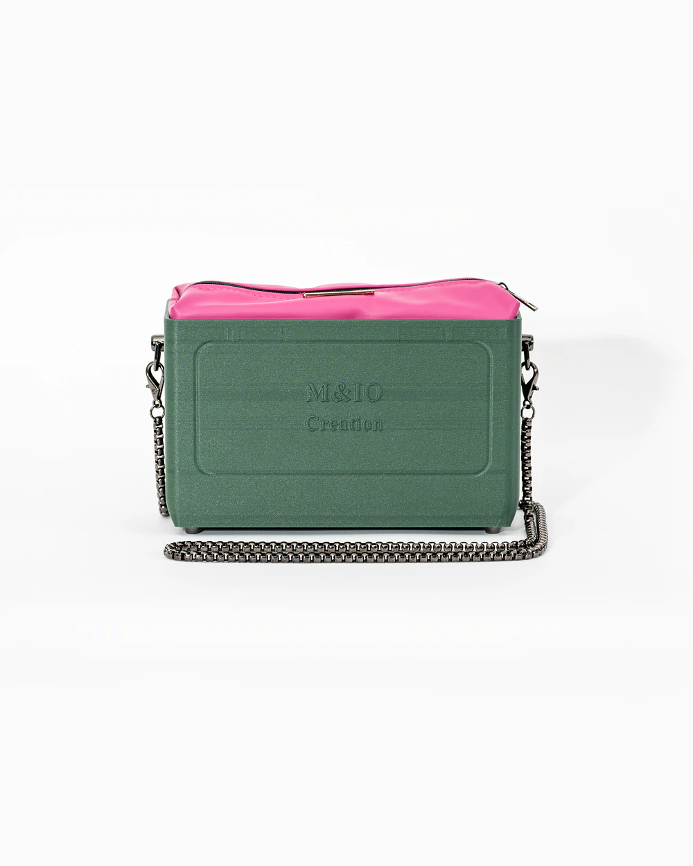 Borsa M&IO 01 di tre quarti: scocca ulivi di puglia opaca con la scritta M&IO Creation in rilievo sul fronte, pochette fucsia che sporge dal bordo superiore, catena in metallo canna di fucile.
