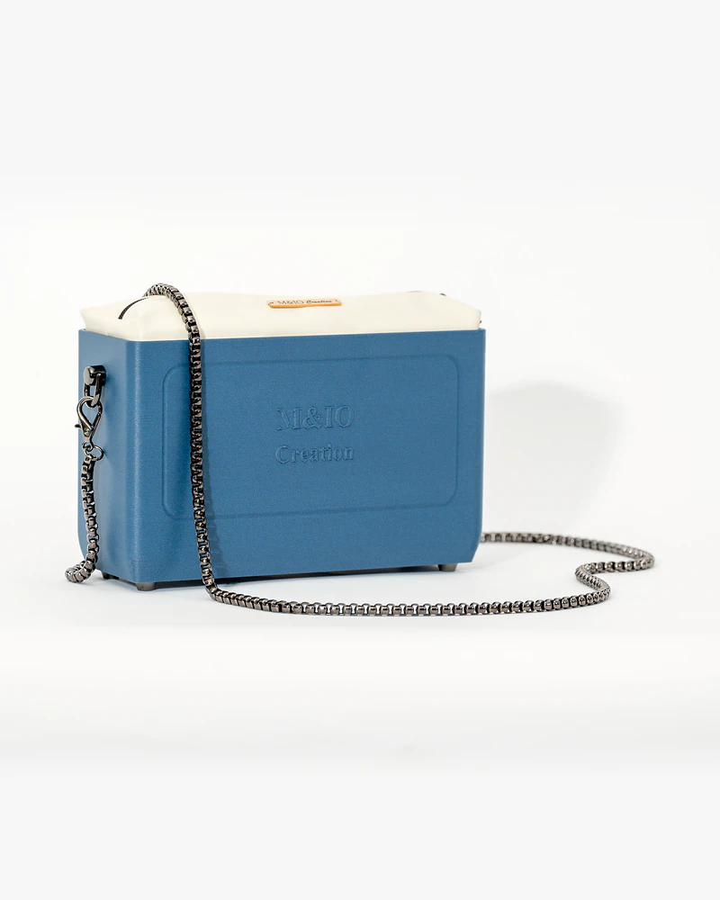 Borsa NYRA Blu Portofino di tre quarti, con la catena: sul fronte si legge in rilievo la scritta M&IO Creation.